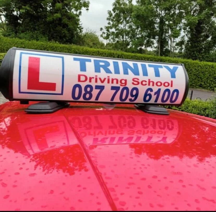 Trinity Driving School roof sign on the school car in Navan, with L plate and the number 087 709 6100